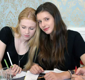 two ib students writing in their notebooks during class